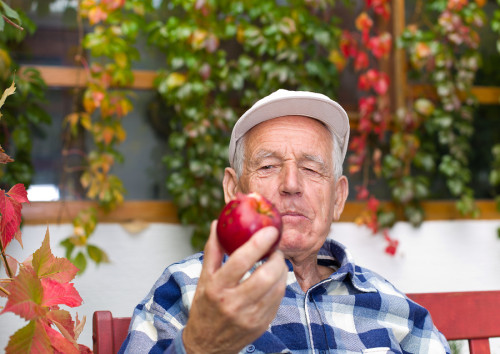 senior man with heart disease looking at apple