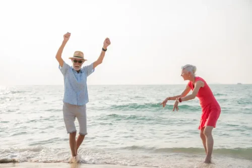 Joyful senior couple dancing and playing at the beach