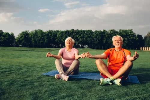 Senior couple meditating together on yoga mats outdoors