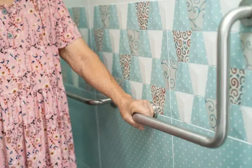 Elderly woman gripping bathroom safety grab bar for support