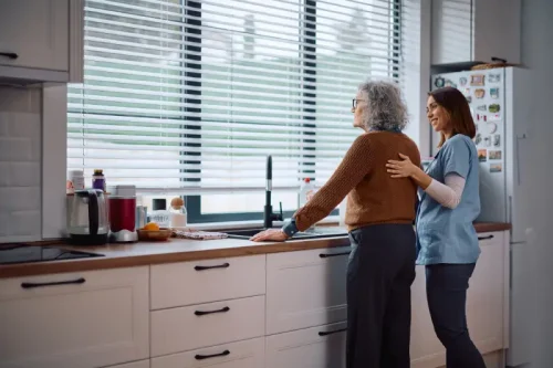 Young caregiver assisting elderly woman in bright kitchen